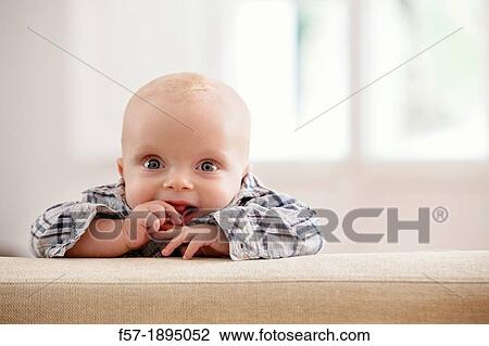 Six month year old baby holding on to the back of a sofa View Large Photo Image Stock Image - Six month year old baby holding on to the back of a sofa. Fotosearch