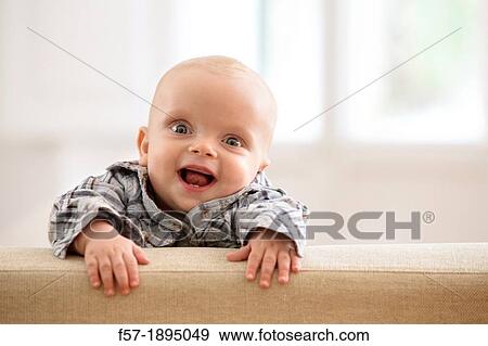 Six month year old baby holding on to the back of a sofa View Large Photo Image Stock Photo - Six month year old baby holding on to the back of a sofa. Fotosearch