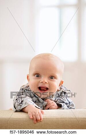 Six month year old baby holding on to the back of a sofa View Large Photo Image Stock Photograph - Six month year old baby holding on to the back of a sofa. Fotosearch