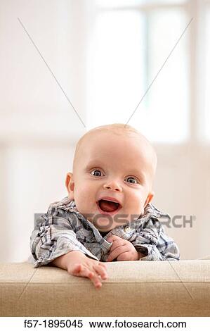 Six month year old baby holding on to the back of a sofa View Large Photo Image Stock Photography - Six month year old baby holding on to the back of a sofa. Fotosearch