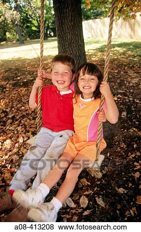 Six year old boy and girl are all smiles as they swing together. View Large Photo Image Stock Photo - Six year old boy and girl are all smiles as they swing together.. Fotosearch