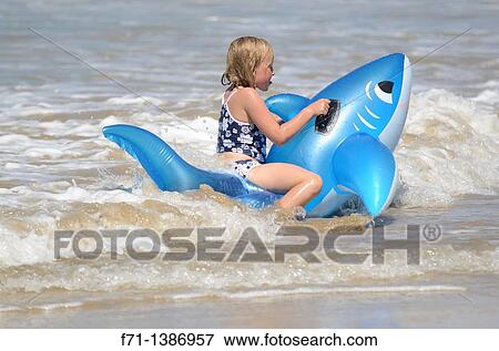 Six year old girl at the beach playing in the surf on inflatable shark Mimiwhangata Northland, New Zealand View Large Photo Image Stock Photo - Six year old girl at the beach playing in the surf on inflatable shark Mimiwhangata Northland, New Zealand. Fotosearch