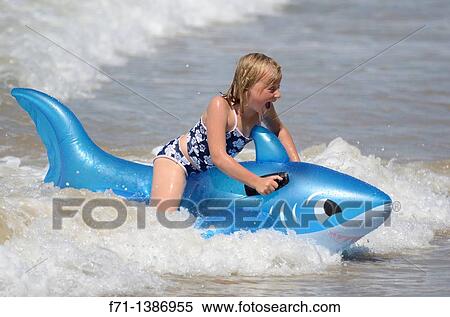 Six year old girl at the beach playing in the surf on inflatable shark Mimiwhangata Northland, New Zealand View Large Photo Image Stock Photography - Six year old girl at the beach playing in the surf on inflatable shark Mimiwhangata Northland, New Zealand. Fotosearch