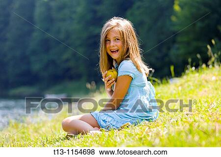 Six year old girl is laughing and holding a pear View Large Photo Image Stock Photo - Six year old girl is laughing and holding a pear. Fotosearch