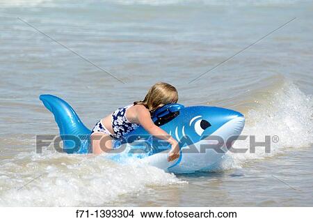 Six year old girl playing in the surf on inflatable shark Mimiwhangata Northland, New Zealand View Large Photo Image Picture - Six year old girl playing in the surf on inflatable shark Mimiwhangata Northland, New Zealand. Fotosearch