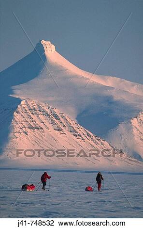 Stock Image - Ski tourers hauling sledges on spring traverse Ny Alesund to Longyearbyen Spitsbergen Island Svalbard Norwegian Arctic. Fotosearch