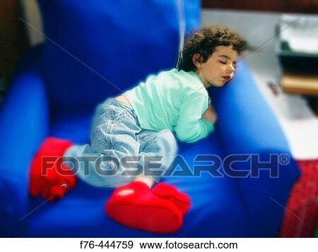 Stock Photo - Sleeping child with large red slippers. Fotosearch
