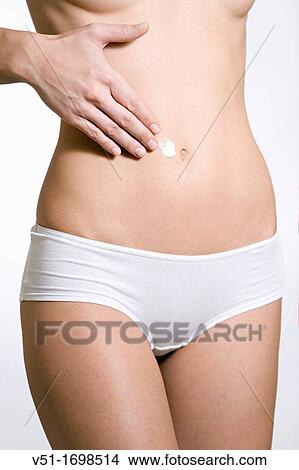 Slender woman applying lotion to her stomach View Large Photo Image Picture - Slender woman applying lotion to her stomach. Fotosearch