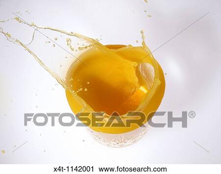 Stock Image - slice of orange splashing into a glass of orange juice from above. Fotosearch
