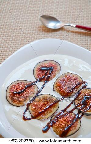 Stock Image - Sliced figs with cream and chocolate syrup. Close view.. Fotosearch