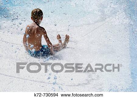 Slipping down a water slide at a waterpark through water spraying is fun and refreshing on a hot summer day View Large Photo Image Picture - Slipping down a water slide at a waterpark through water spraying is fun and refreshing on a hot summer day. Fotosearch