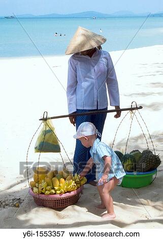 Small boy grabs banana bunch conical hat woman fruit vendor looks on Long Beach Phu Quoc Island Vietnam View Large Photo Image Stock Photo - Small boy grabs banana bunch conical hat woman fruit vendor looks on Long Beach Phu Quoc Island Vietnam. Fotosearch