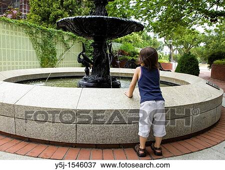 Small child leans on a water fountain to get a better look View Large Photo Image Stock Photo - Small child leans on a water fountain to get a better look. Fotosearch