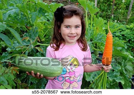 Stock Photo - Small girl with big carrot and courgette, Primorsk, Russia.. Fotosearch