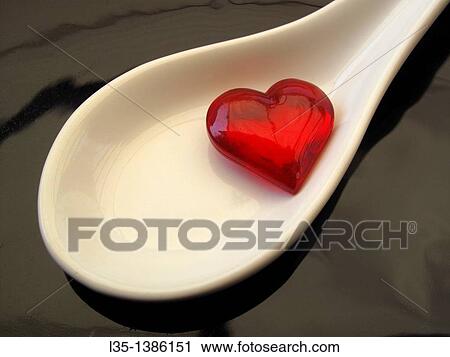 Stock Image - Small glass heart is in medicine spoon. Fotosearch