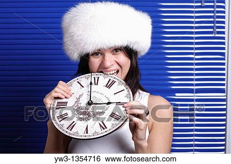 Smiling beautiful womanbiting the clock against louvers View Large Photo Image Stock Photograph - Smiling beautiful womanbiting the clock against louvers. Fotosearch