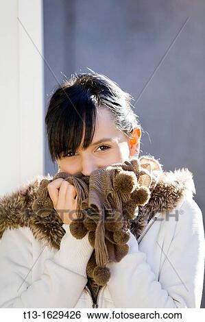 Stock Photograph - Smiling behind a scarf young woman portrait. Fotosearch