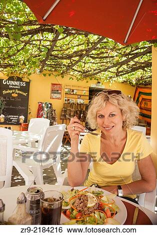 Smiling blond woman eating tuna salad for lunch at an outdoor cafe, Barrydale, Little Karoo, South Africa. View Large Photo Image Stock Photograph - Smiling blond woman eating tuna salad for lunch at an outdoor cafe, Barrydale, Little Karoo, South Africa.. Fotosearch