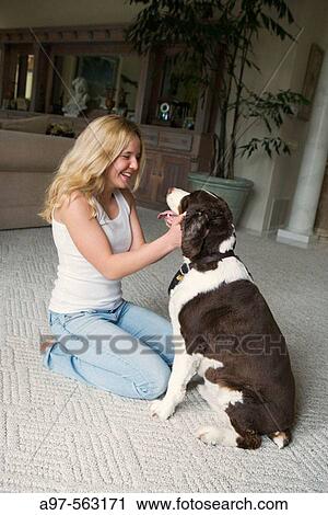 Smiling blonde teen girl in blue jeans and white tank top kneeling, caressing her pet dog's face. View Large Photo Image Stock Image - Smiling blonde teen girl in blue jeans and white tank top kneeling, caressing her pet dog's face.. Fotosearch