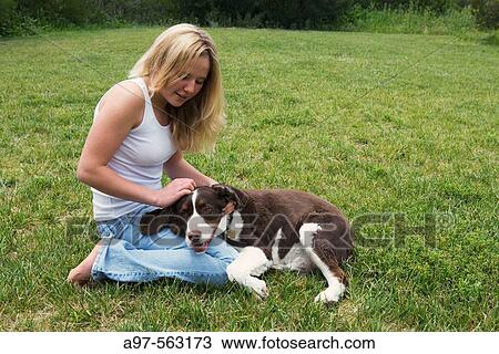 Smiling blonde teen girl in blue jeans and white tank top kneeling on grass lawn, pets her dog's head resting on her leg. View Large Photo Image Stock Image - Smiling blonde teen girl in blue jeans and white tank top kneeling on grass lawn, pets her dog's head resting on her leg.. Fotosearch