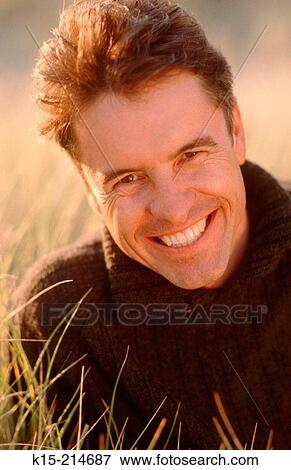 Smiling man in long grass View Large Photo Image Stock Photo - Smiling man in long grass. Fotosearch