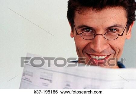Stock Photograph - Smiling man looking over his newspaper. Fotosearch