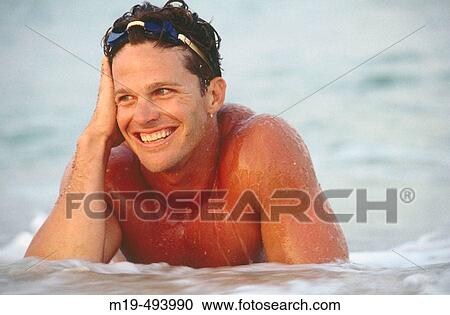 smiling man lying in the surf View Large Photo Image Stock Image - smiling man lying in the surf. Fotosearch