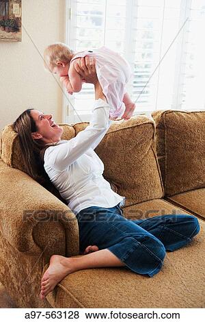 Smiling mother holds blonde infant girl above her head. View Large Photo Image Stock Photo - Smiling mother holds blonde infant girl above her head.. Fotosearch
