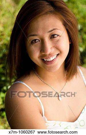 Stock Photo - Smiling portrait of an Asian young woman in a field or garden. Fotosearch