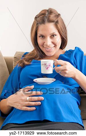 Smiling pregnant woman drinking coffee View Large Photo Image Stock Photo - Smiling pregnant woman drinking coffee. Fotosearch