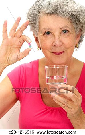 smiling senior woman holding a colored tablet and a glass of water for her medical treatment View Large Photo Image Stock Photograph - smiling senior woman holding a colored tablet and a glass of water for her medical treatment. Fotosearch