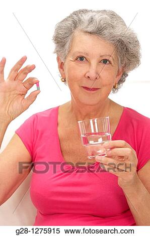 smiling senior woman holding a colored tablet and a glass of water for her medical treatment View Large Photo Image Stock Photography - smiling senior woman holding a colored tablet and a glass of water for her medical treatment. Fotosearch