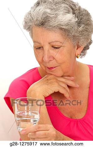 smiling senior woman holding a glass of water View Large Photo Image Stock Photo - smiling senior woman holding a glass of water. Fotosearch