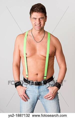 Stock Image - Smiling shirtless man with suspenders, looking at camera. Fotosearch