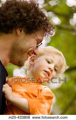 Smiling young father carrying his two year old son on his arm View Large Photo Image Stock Photo - Smiling young father carrying his two year old son on his arm. Fotosearch