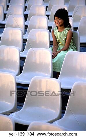 Smiling young girl seated alone among unoccupied seats, France View Large Photo Image Picture - Smiling young girl seated alone among unoccupied seats, France. Fotosearch