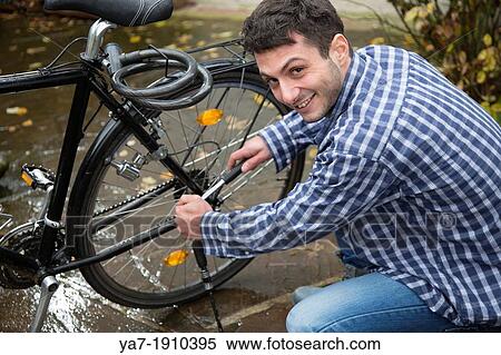 Stock Photography - Smiling Young Man Repairing Bicycle. Fotosearch