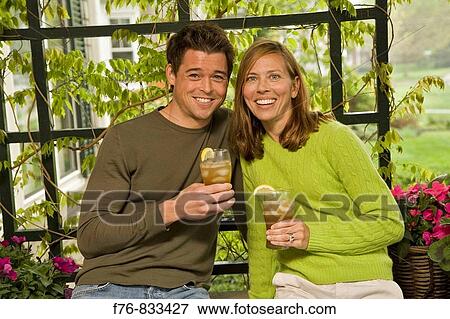 Smiling young married couple 35ish on front porch holding glasses of iced tea View Large Photo Image Stock Photo - Smiling young married couple 35ish on front porch holding glasses of iced tea. Fotosearch