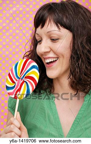 Smiling young woman holding lollypop View Large Photo Image Stock Photograph - Smiling young woman holding lollypop. Fotosearch