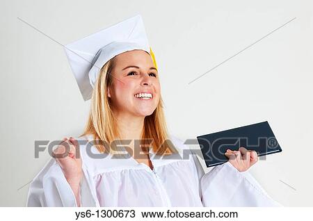 Stock Image - Smiling Young Woman in White Graduation Cap and Gown with Diploma. Fotosearch