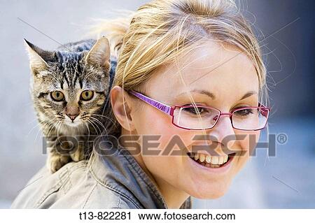 Smiling young woman is holding small cat on her shoulders View Large Photo Image Stock Image - Smiling young woman is holding small cat on her shoulders. Fotosearch