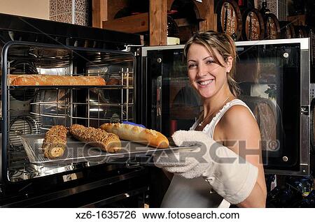 smiling young woman removing the bread from the oven View Large Photo Image Stock Photograph - smiling young woman removing the bread from the oven. Fotosearch