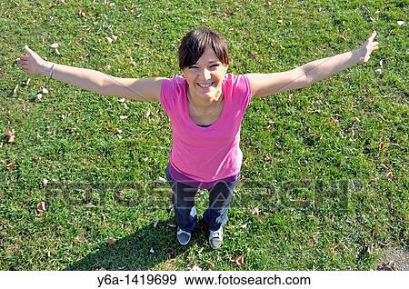 Smiling young woman standing outdoors with open arms View Large Photo Image Stock Photo - Smiling young woman standing outdoors with open arms. Fotosearch