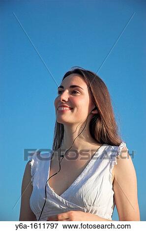 Smiling young woman wearing earphones outdoors View Large Photo Image Stock Photo - Smiling young woman wearing earphones outdoors. Fotosearch