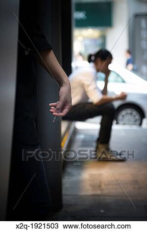 Stock Image - Smokers hidign in an alley Hong Kong. Fotosearch