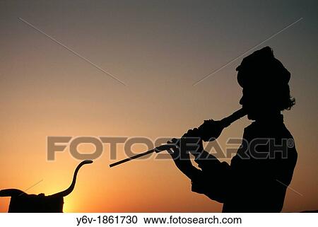 Stock Image - Snake charmer at sunset. Rajasthan, India.. Fotosearch