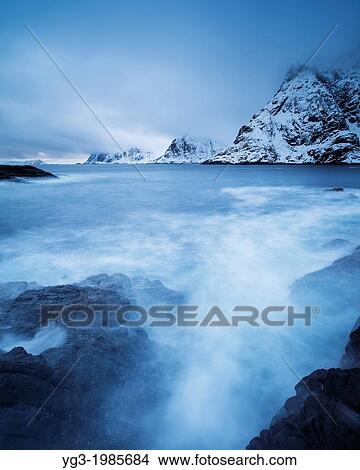 Picture - Snow covered mountains rise from sea,?, Moskenesoy, Lofoten Islands, Norway. Fotosearch