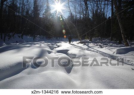 Stock Photograph - Snowshoeing along Franconia Brook during the winter months in Lincoln, New Hampshire USA. Fotosearch