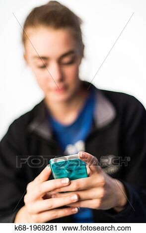 Stock Image - Soft focus of a girl, 17, using a smart phone. Fotosearch