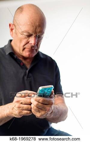 Stock Photo - Soft focus on a smart phone, used by a middle-aged man. Fotosearch